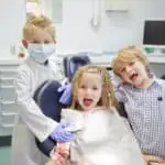 three young kids in dental office playing dentist