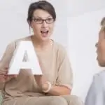 woman holding letter A, speaking with young boy